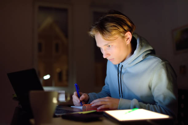 skoncentrowany nastolatek uczący się późno w nocy w domowym biurze z laptopem i tabletem. - addiction internet computer working late zdjęcia i obrazy z banku zdjęć