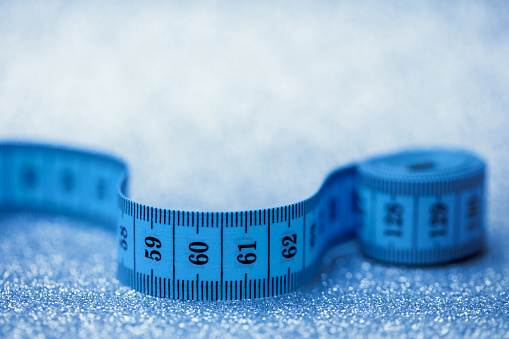 Close-up of a rolled up tape measure on a sparkling background. Shallow depth of field, space for copy.