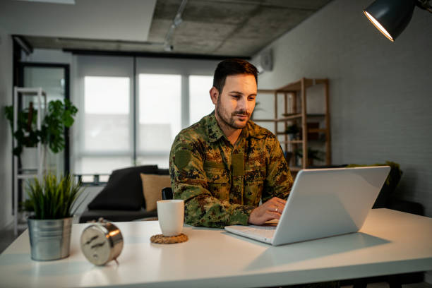 Army man using laptop at home stock photo