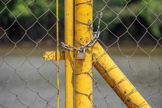 yellow wire mesh metal gate locked with chain and padlock