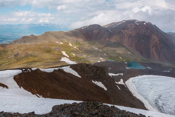 istock Dramatic landscape with contrast between sunny and rainy weather. Awesome scenery with sharp rocks and small lake in mountain valley. Changeable weather in mountains is sunny and cloudy at same time. 1433224748