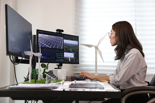 Retrato Hermosa mujer asiática trabaja en computadora con modelo de turbina eólica y panel solar, célula solar. Concepto de sostenibilidad de energías renovables. Diseño de cubierta de banner para electricidad. photo