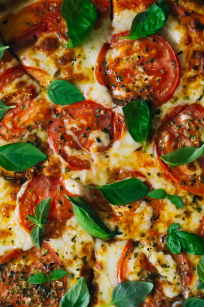 Tasty Homemade margherita pizza with with Tomatoes, Basil and Mozzarella Cheese on wooden background, top view.