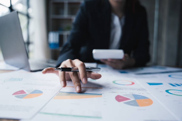 istock business people using calculator for calculating  and pointing pen at statistics chart,  analyze business and marketing growth on financial document data graph. 1433235389