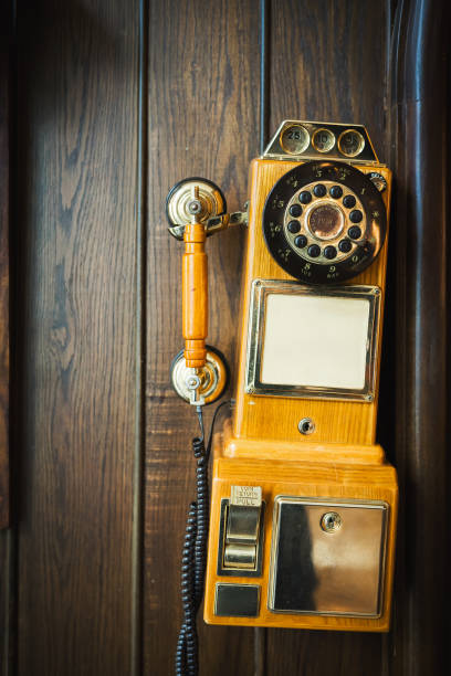 Old vintage rotary telephone hanging on a wooden wall stock photo