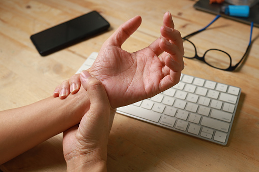 Close-up woman massaging her arthritic hand and wrist, she is suffering from pain and rheumatism.