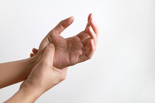 Close-up woman massaging her arthritic hand and wrist, she is suffering from pain and rheumatism.