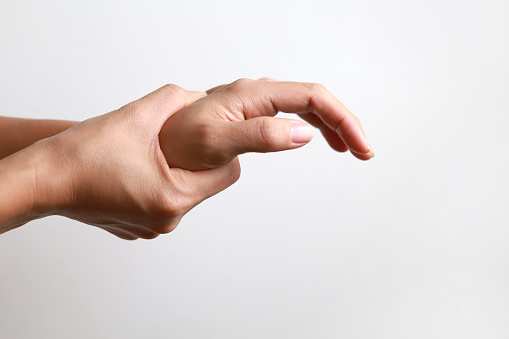 Close-up woman massaging her arthritic hand and wrist, she is suffering from pain and rheumatism.