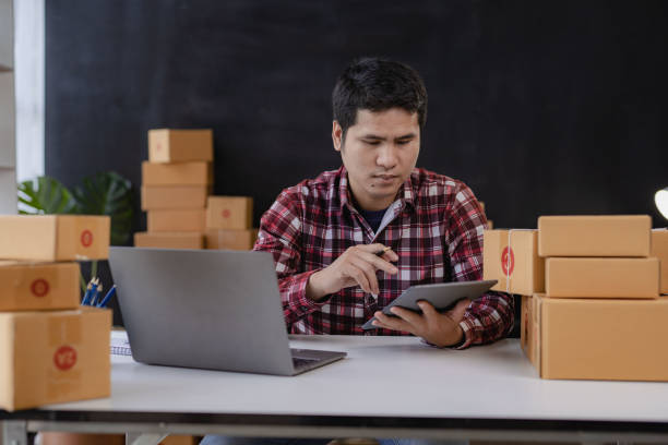 istock Young Asian men start selling online with boxes and laptops for taking orders and shipping parcel boxes, SME business idea. 1433250003