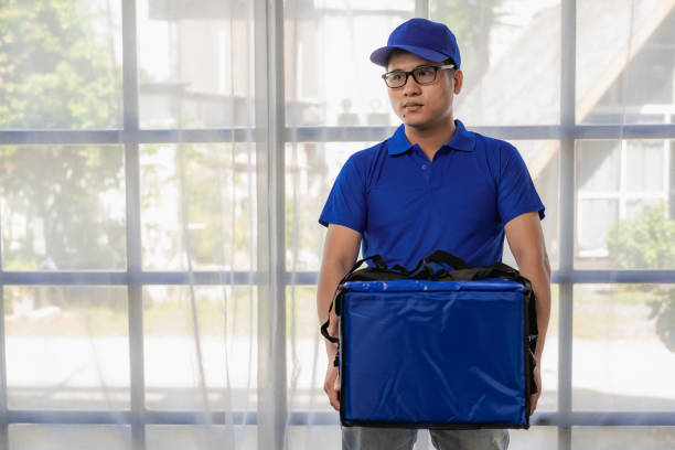 The delivery man was wearing a blue uniform and a bag. Deliver food or express parcel. Delivery man or express parcel isolated on white background. The delivery man was wearing a blue uniform and a bag. Deliver food or express parcel. Delivery man or express parcel isolated on white background. mark goodson screening room stock pictures, royalty-free photos & images