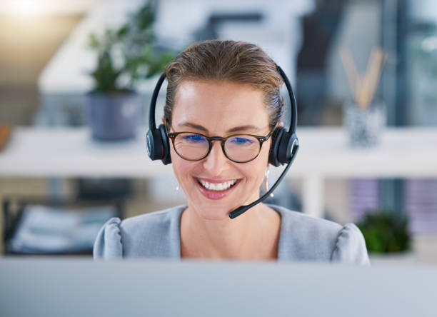 istock Call center agent helping clients online while talking on a headset in a modern office, enjoying her career. Customer service and support with a happy, friendly woman excited to guide and answer 1433257578