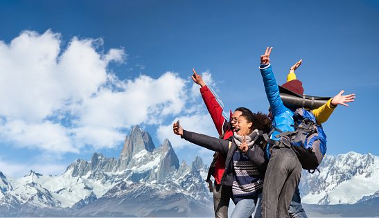 Group of hikers taking selfie on snowy mountains - Happy friends with hands up having fun together - Multiethnic people having trekking day out together