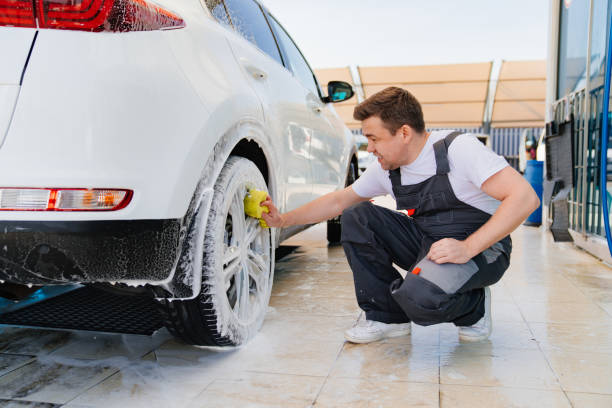 istock self-service car wash. a man in a work jumpsuit washes the wheels with a sponge 1433263236