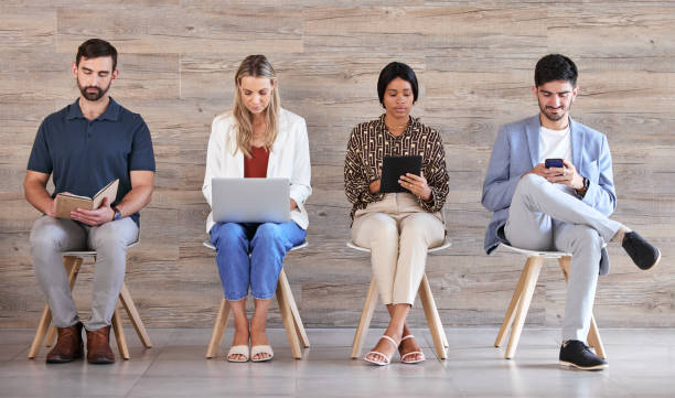 istock Business people waiting at interview or recruitment for work in a line, networking on tablet, cellphone and planning in a office together. Corporate employee, worker and professional at job center 1433263289