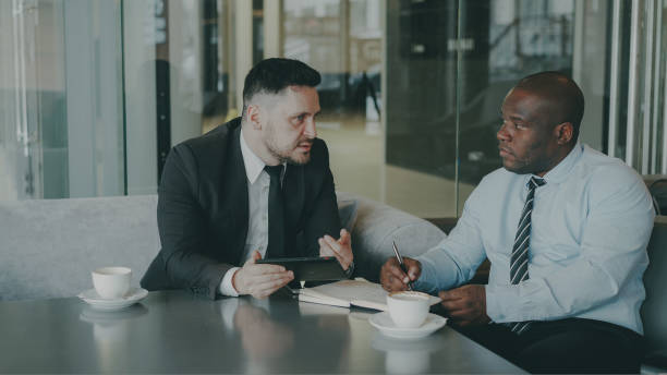 istock Two ambitious business partners looking through their contract and singing it at their table with laptop and graphs in airy cafe. 1433264866