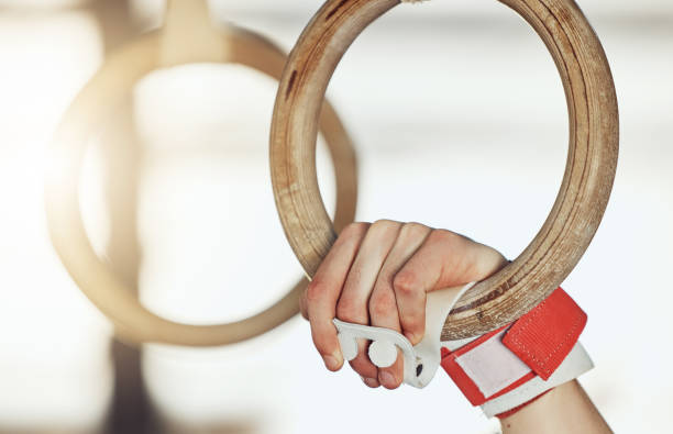 Hands of man gymnast training on rings for strong muscle power exercise and sport fitness performance goal. Healthy sports athlete or aerobic talent train on gym equipment for competition workout manos del hombre gimnasta entrenando en anillos para un fuerte ejercicio de potencia muscular y un objetivo de rendimiento de acondicionamiento físico deportivo. atleta deportivo saludable o entrenamiento de talento aeróbico en equipos de gimnasio para e