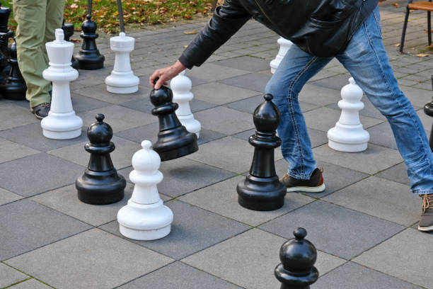Two unrecognizable middle-aged males play a game of chess in a public park.