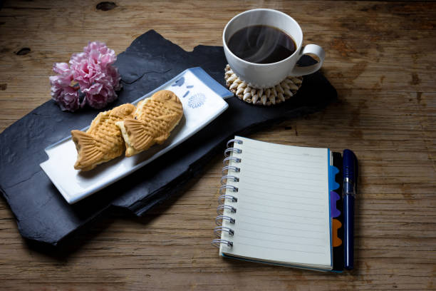 Taiyaki cakes, coffee,notebook on wood background