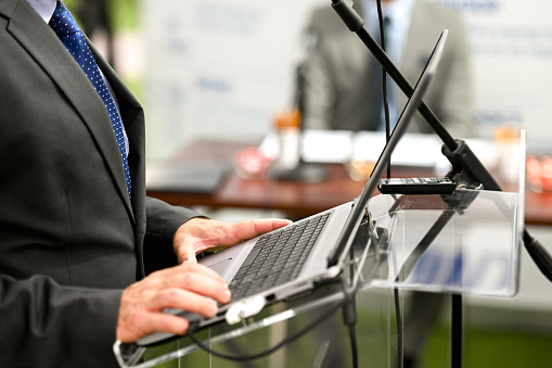 Close up of businessman standing behind lectern, preparing before the start of the conference