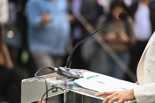 Unrecognizable woman delivering speech, standing behind lectern