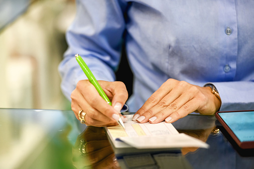Close-up of saleswoman settling the accounts, holding pen in her right hand