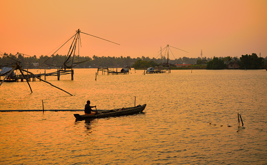 Kochi, India - February 20, 2018: A fisherman rowing a boat in Kerala backwaters during sunset.