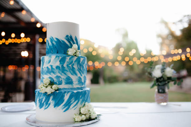 istock THree tiered white and blue wedding cake with white roses and heart topper. 1433274902