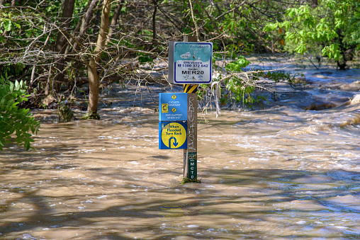 Melbourne, Victoria, Australia, October 14th, 2022: A wooden flood marker post surrounded by the rushing waters of Merri Creek
