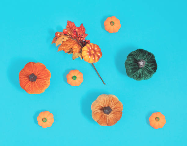 Artificial pumpkins, autumn leaves and berries lay down on blue bacground