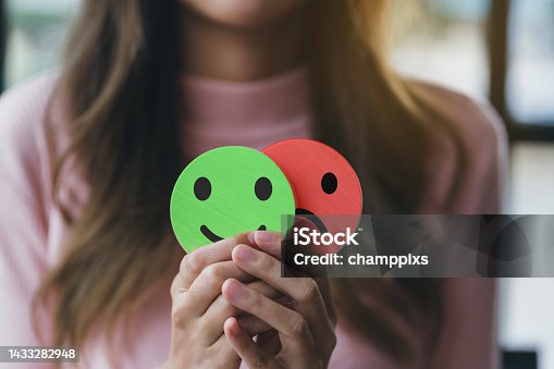 istock Woman Hands holding sad face hiding or behind happy smiley face, bipolar and depression, mental health concept, personality, mood change, therapy healing split concept. 1433282948