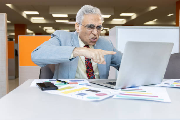 istock Displeased senior man using laptop at office. 1433285382
