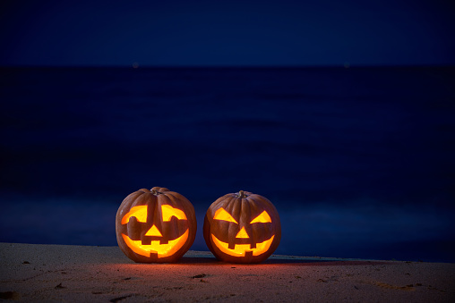 Halloween pumpkins jack p lanterns on the sea beach at night in the bright moonlight