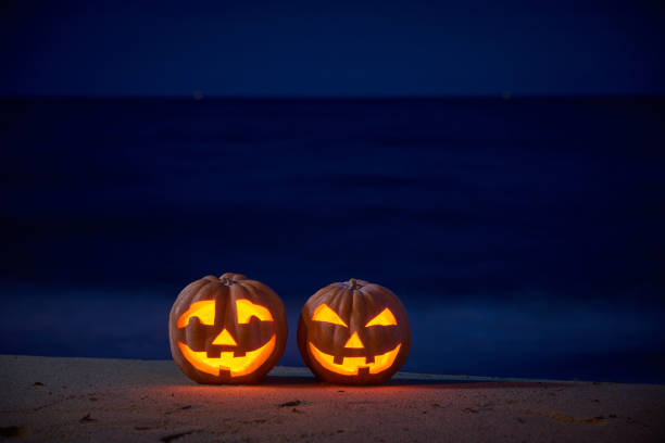 Halloween pumpkins jack p lantern on the sea beach at night in the bright moonlight stock photo
