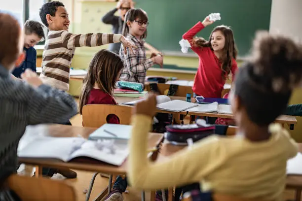 Large group of school kids making chaos during a class in the classroom.