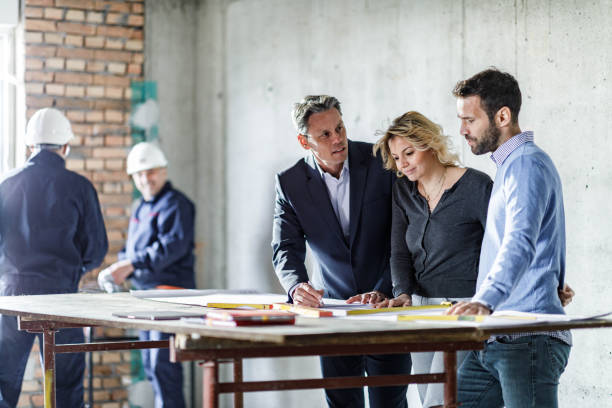istock Young couple and their agent examining blueprints at construction site. 1433288947
