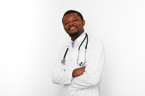 Smiling black bearded doctor man crossed arms in white coat with stethoscope isolated on white background. Adult black african american physician therapist portrait, confident candid male emotion