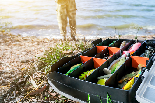 Fishing tackle with wobblers on the background of a fisherman. Fisherman's tackle box fully stocked with lures and gear for fishing. Fishing lures and accessories
