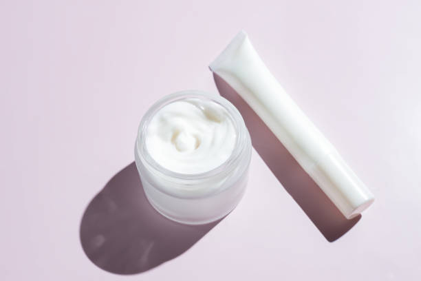 istock Face and eye cream in white unbranded packaging on pink background with harsh shadows. Skin care daily products for healthy and fresh skin. Packaging design 1433290440