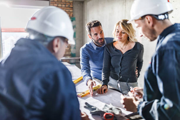 istock Happy couple talking to manual workers about blueprints at construction site. 1433290522