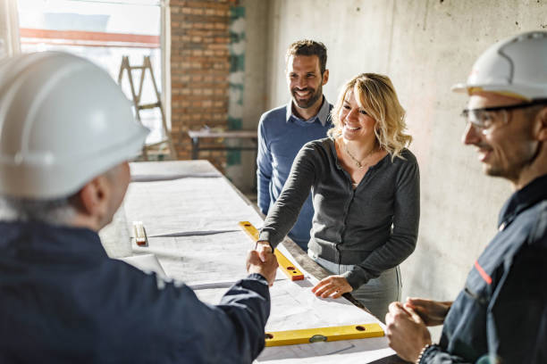 istock Happy couple closed a deal with manual workers at construction site. 1433290578
