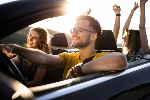 istock Group of happy friends having fun while going on a trip in a convertible car. 1433292106