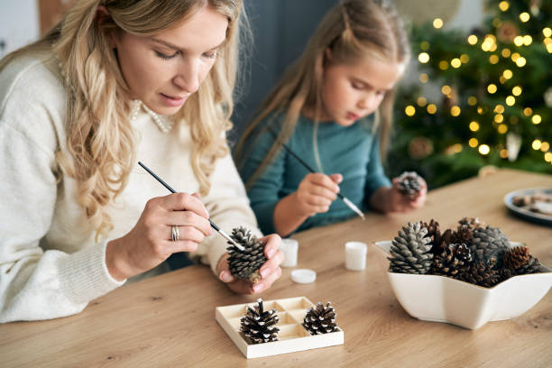 istock Caucasian woman and daughter decorating cone with white paint 1433294488