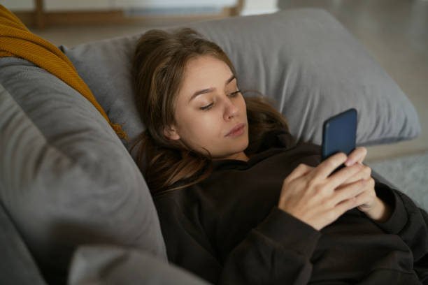 istock Caucasian woman lying down on the couch and using mobile phone 1433295290
