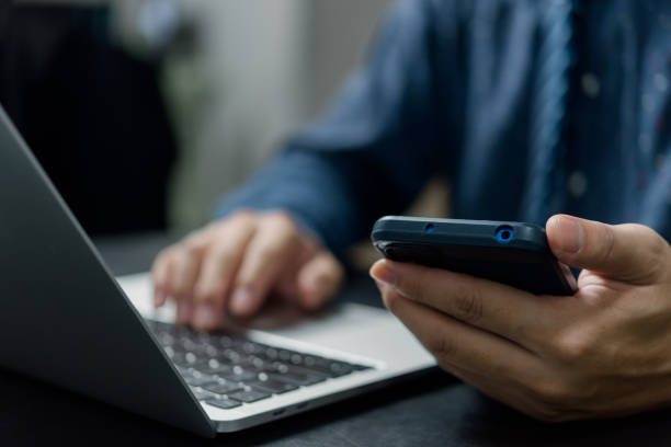 istock Man hand holding mobile smartphone digital technology network communications at desk. 1433295526