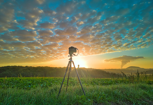 View of the silhouette of camera on a tripod shooting the sunrise