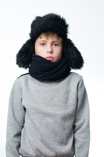 Portrait of a boy on a white background in a hat with ears and a scarf, a black scarf and a black hat with ears.