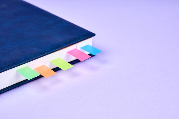istock An office notepad with colorful sticky page markers sandwiched between pages on purple background 1433298540