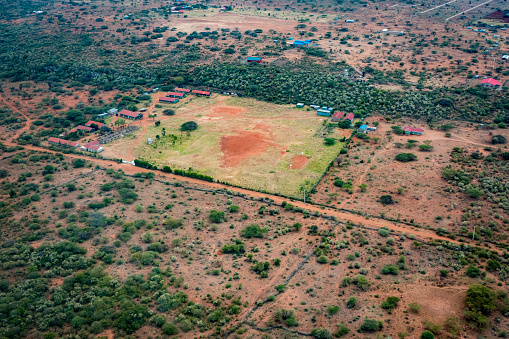 Somewhere in the land of the Masai, Kenya - March 24th 2022. Picture shows the Ng'arooj Secondary School surrounded by tin shacks and residential houses in the middle of nowhere in the Kenyan savannah during dry season.