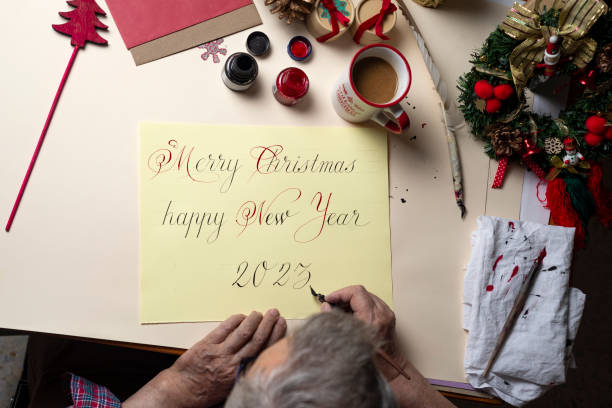 英語の手書きでクリスマスカードを書く老人の手の上面図。 - inoki antonio ストックフォトと画像