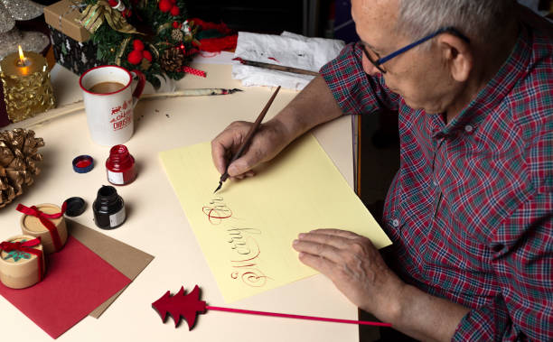年配の男性  がペンとインクと英語の書道でクリスマスカードを書く。手書き書道 - inoki antonio ストックフォトと画像